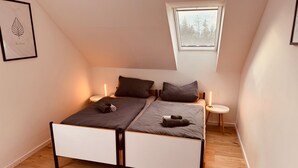 Ein Schlafzimmer mit einem Bett, zwei Nachttischen, einem Fenster und einem gerahmten Bild an der Wand.