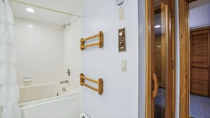 Une salle de bain avec une baignoire, une douche et une porte en bois.
