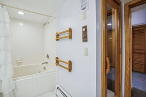 Een badkamer met een badkuip, douche en een houten deur.