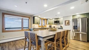 Eine moderne Küche mit einer zentralen Kochinsel, Holzstühlen und einem Edelstahl-Kühlschrank.