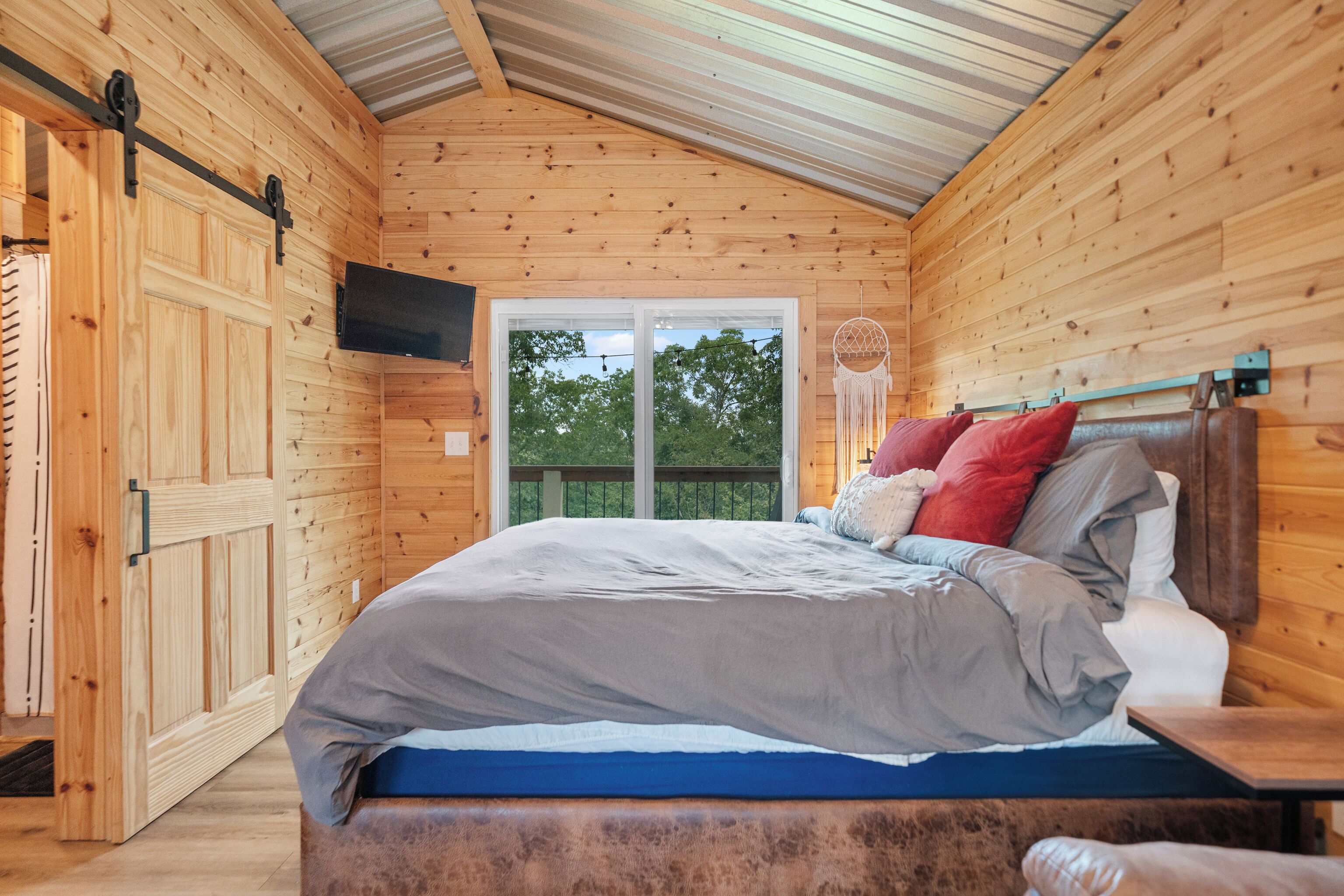 Ein Schlafzimmer einer Holzhütte mit Bett, Fernseher und einer Schiebetür.