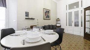 A dining area with a round table set for four, a sofa, and a door with frosted glass panels. - Italianway Easy - Ozieri 7 (Milan)