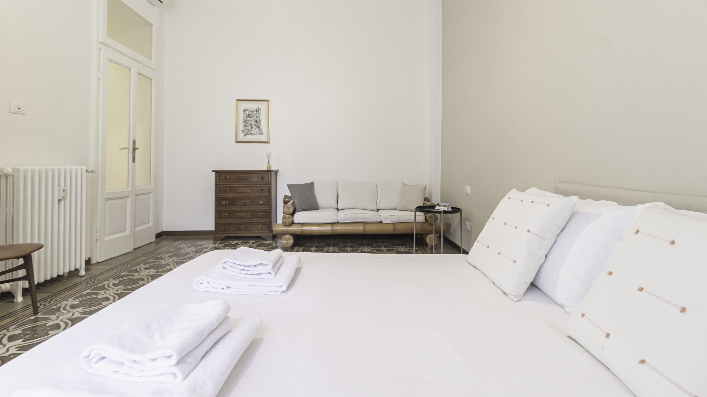 A bedroom with a bed, a nightstand, a dresser, and a framed picture on the wall.