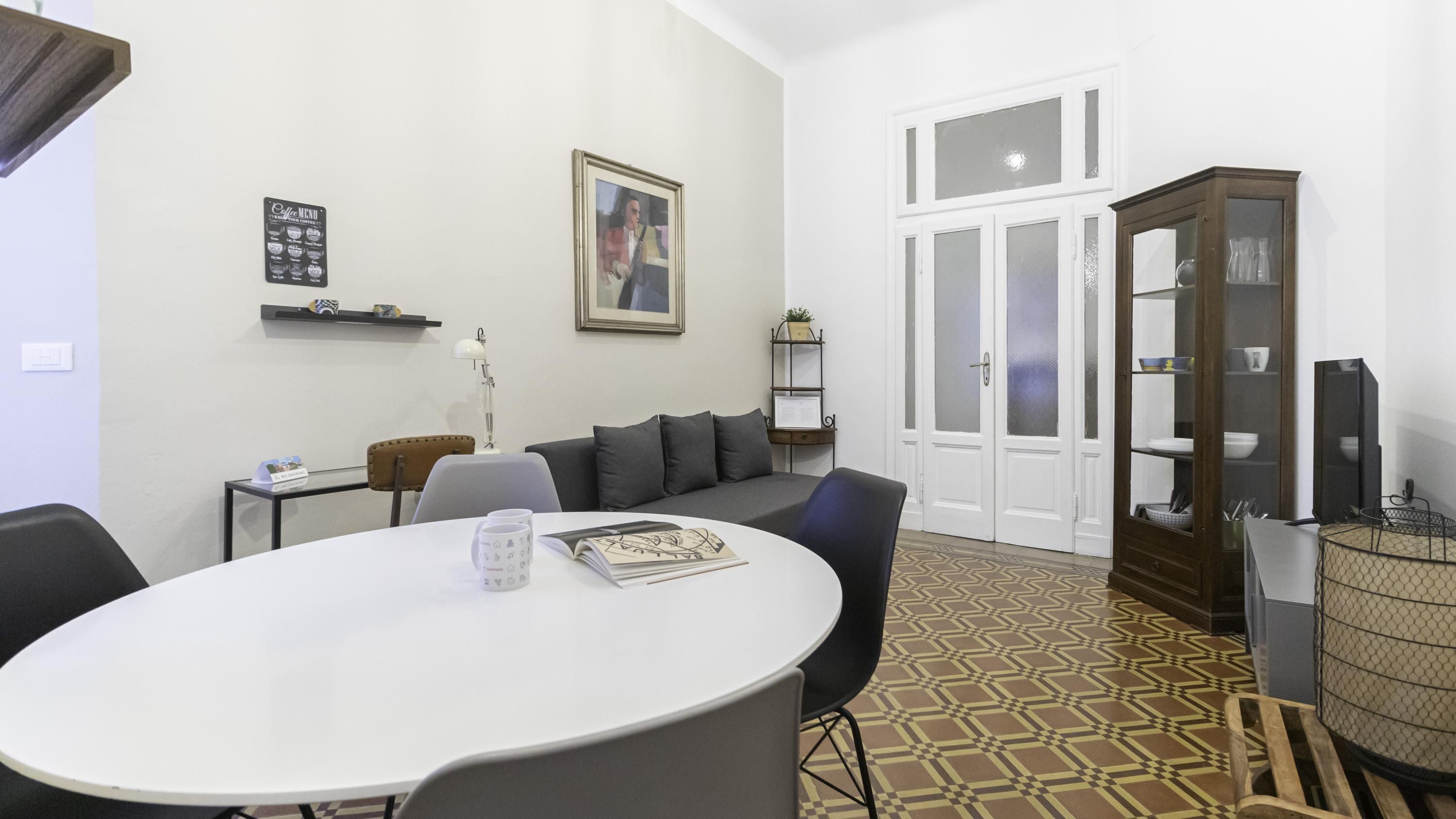 A modern living room with a round dining table, a sofa, a cabinet, and a framed picture on the wall.
