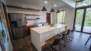 A modern kitchen with a large island, bar stools, and a view of the outdoors. - Chial Reserve (San Ignacio)