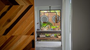 A hallway with a wooden floor, a white wall, and a window with a view of greenery. - Chial Reserve (San Ignacio)