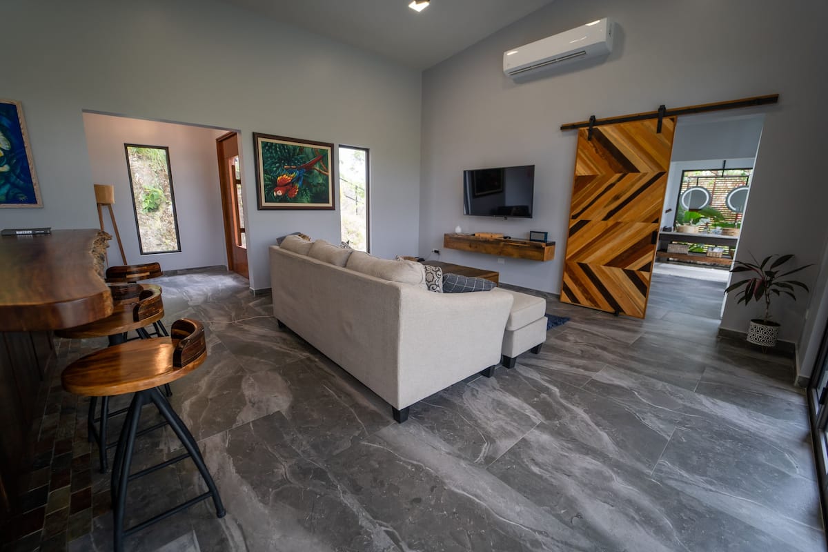 Una sala de estar moderna con un sofá, un televisor y un separador de madera.