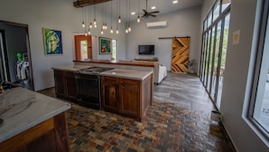 A modern kitchen with a large island, pendant lighting, and a view of the outdoors. - Chial Reserve (San Ignacio)