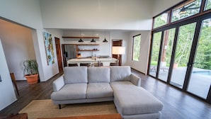 A modern living room with a sectional sofa, a wooden coffee table, and a kitchen in the background. - Chial Reserve (San Ignacio)
