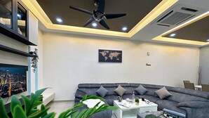 Un salon moderne avec un canapé d’angle gris, une table basse blanche et un ventilateur de plafond.