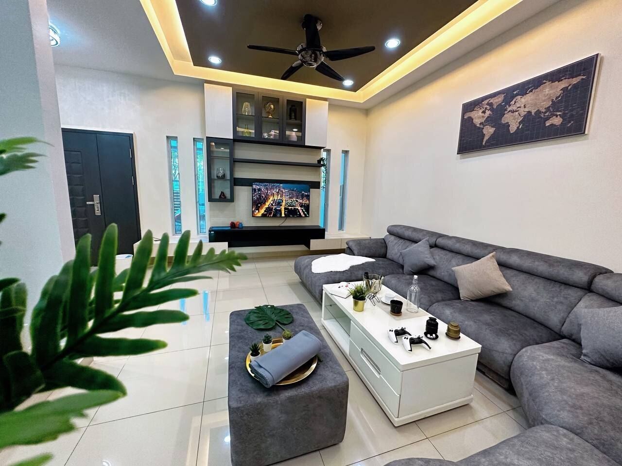 Un salon moderne avec un canapé gris, une table basse blanche et un téléviseur fixé au mur.