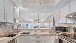 A modern kitchen with white cabinets, a marble countertop, and stainless steel appliances. - Gorgeous bay views from this ground floor Siesta Key Condo - GBB 1360 (Siesta Key)