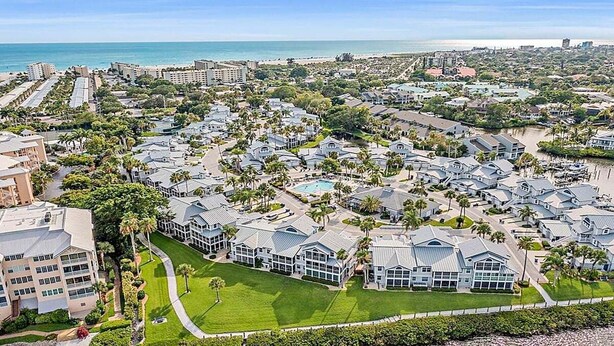 A coastal residential area with multiple houses, a swimming pool, and a view of the ocean. - Gorgeous bay views from this ground floor Siesta Key Condo - GBB 1360 (Siesta Key)