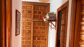 A hallway with wooden doors, a hanging pendant light, and a stack of folded towels on a shelf.
