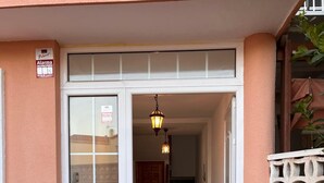 A building entrance with a glass door, a staircase, and a hanging light fixture.