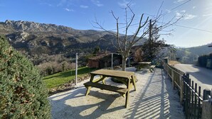 A picnic area with benches, a gravel path, and a view of mountains in the background. - Casa El Marizal 2 Arriondas (Montealea)