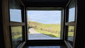 Vista a través de una ventana con cielo despejado, una carretera y colinas verdes.