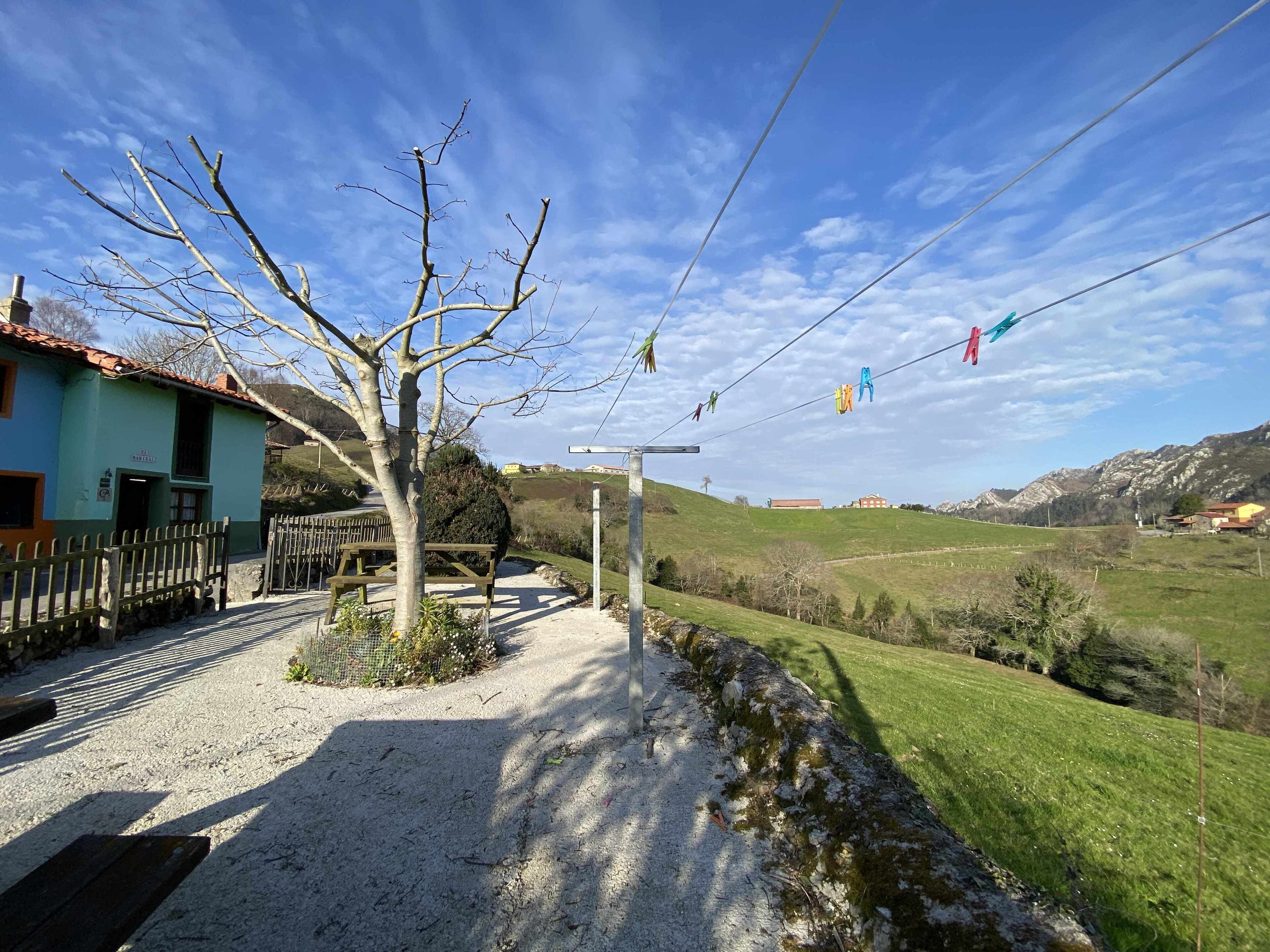 Un paysage rural avec une maison, un chemin de gravier et une colline verdoyante en arrière-plan.