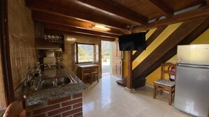 Una cocina con encimeras de granito, salpicadero de ladrillo, refrigerador de acero inoxidable y techo de madera.