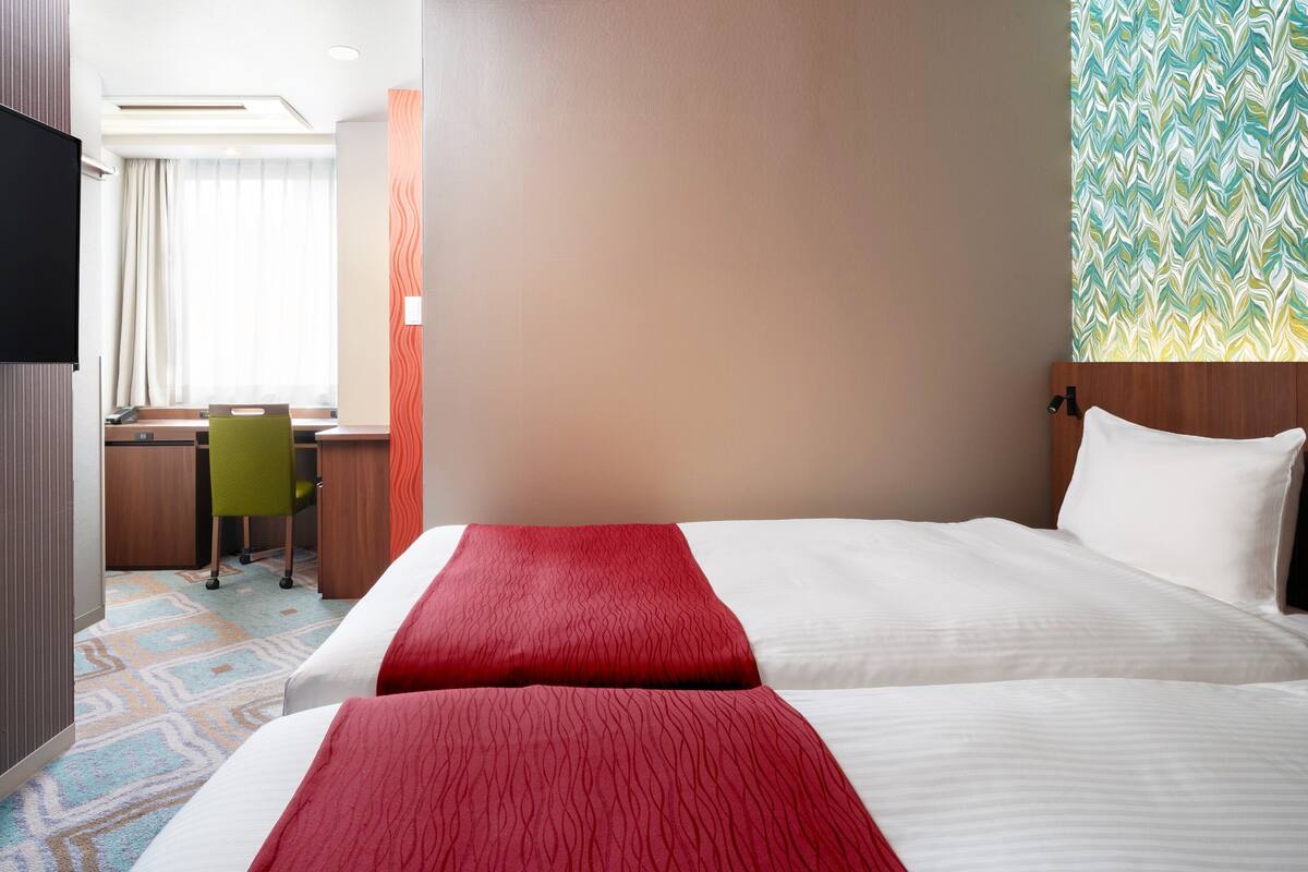 Una habitación de hotel con una cama grande, un escritorio y una silla.