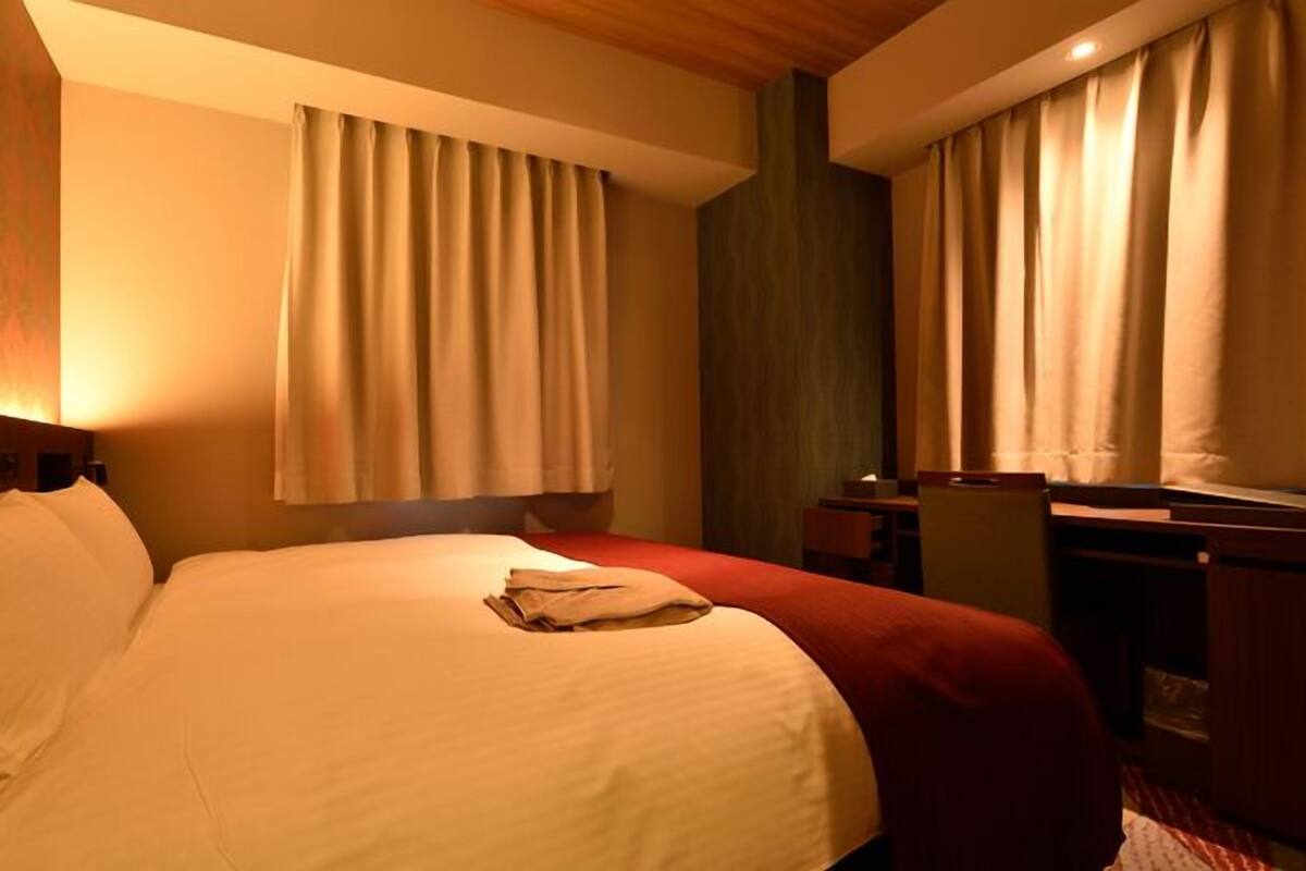 Una habitación de hotel con una cama grande, un escritorio y una silla.