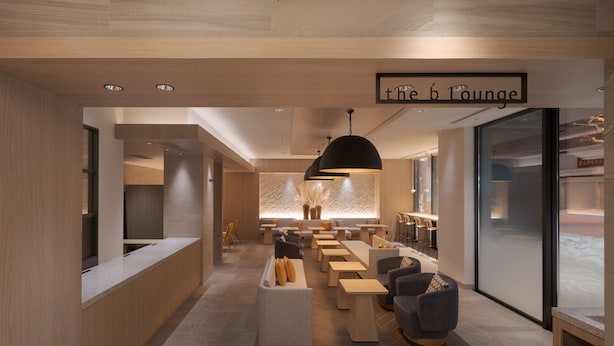 Een moderne loungeruimte met een lange balie, zithoekjes en een grote hanglamp.