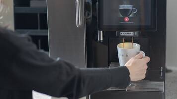 A person using a coffee machine with a digital display, dispensing coffee into a cup.