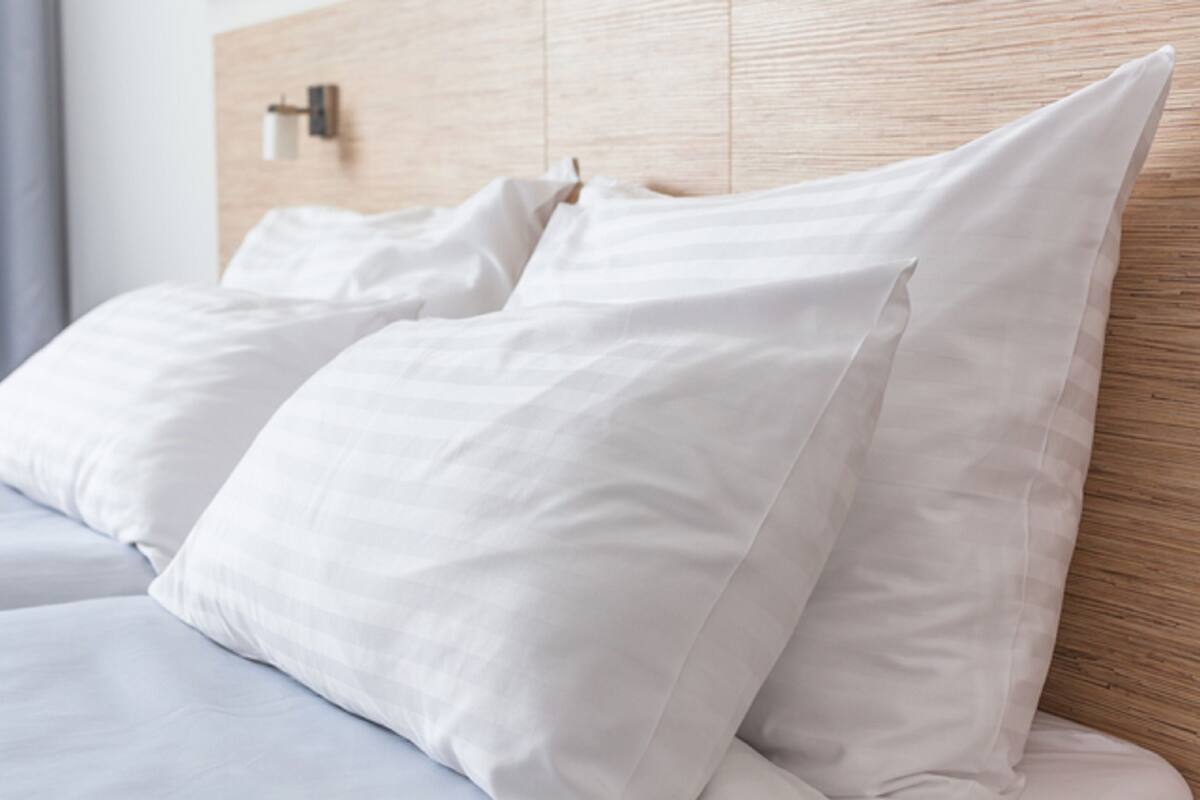 Una cama con sábanas blancas y cabecera de madera.