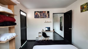Een slaapkamer met een bed, bureau, stoel en kledingkast.
