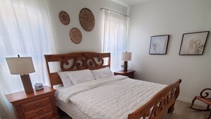 Un dormitorio con una cama de madera, una mesita de noche con lámpara, un aparador y dos lámparas de pared.