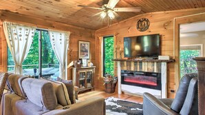 A cozy cabin interior with a fireplace, leather seating, and a television.