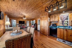 A wooden cabin interior with a dining area, kitchen, and living space.
