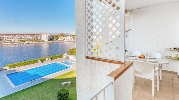 Ein Balkon mit Pool, Essbereich und Blick auf einen Fluss und Gebäude.