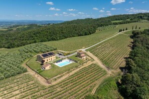An aerial view of a property with a swimming pool, solar panels, and vineyard fields. - Villa Il Caggio - San Gimignano ,Tuscany (San Gimignano)