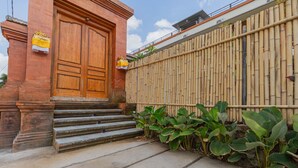 A building with a large wooden door, steps leading up to it, and a bamboo fence.