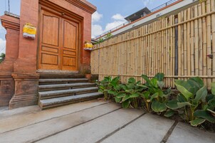 A building with a large wooden door, steps leading up to it, and a bamboo fence.