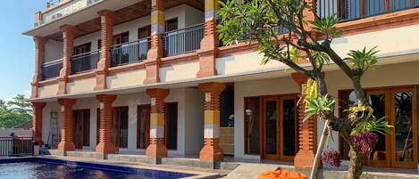 A multi-story building with a swimming pool, outdoor seating, and a well-maintained garden.