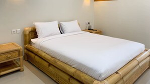 A single bed with white bedding, a wooden headboard, and two wall-mounted light fixtures.
