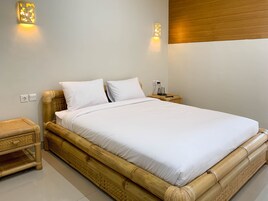 A single bed with white bedding, a wooden headboard, and two wall-mounted light fixtures.
