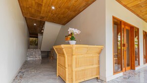 A hallway with a bamboo bench, a potted orchid, and a staircase leading to a wooden door.