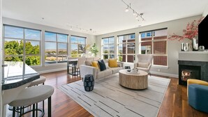 A spacious living room with large windows, a fireplace, and a dining area.