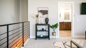A modern hallway with a black console table, a framed artwork, and a potted plant.