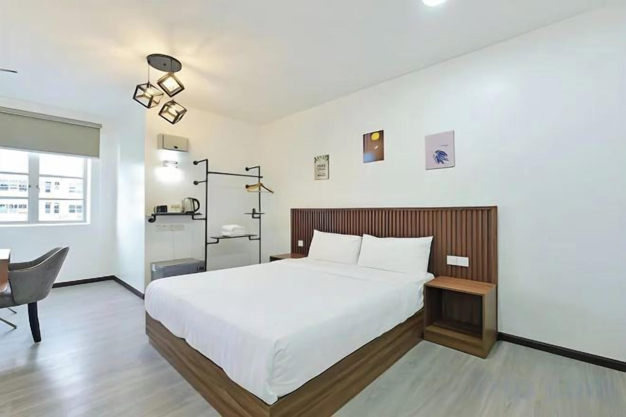 A hotel room with a large bed, bedside table, and a chair.
