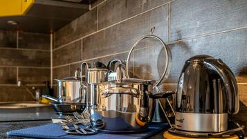 Une cuisine équipée d’appareils électroménagers en acier inoxydable, notamment une bouilloire, des casseroles et une passoire, le tout posé sur un tapis bleu.
