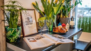 A kitchen counter with a framed sign, two glasses of white wine, a plate of croissants, and a book. - Cute studio for a couple or young family located near parks (Rīga)
