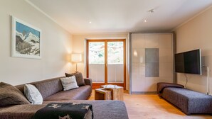 Ein modernes Wohnzimmer mit einer Couch, einem kleinen Tisch und einem an der Wand befestigten Fernseher.