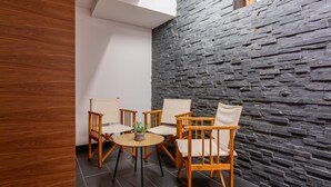 Ein modernes Interieur mit einer Steinwand, Holzstühlen, einem runden Tisch und einem Blumentopf.
