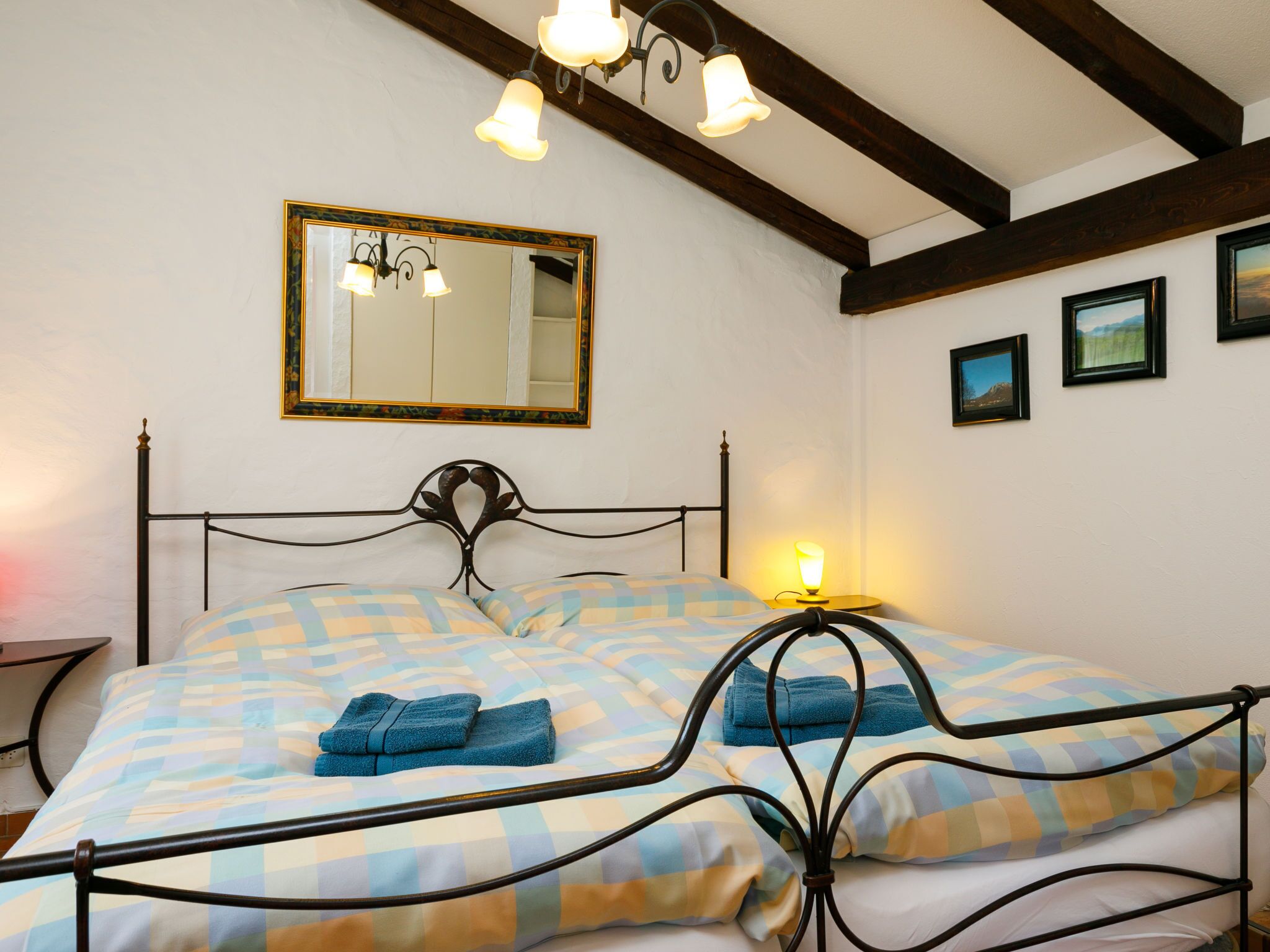 A bedroom with a bed, a nightstand, a mirror, and a wall-mounted light fixture.