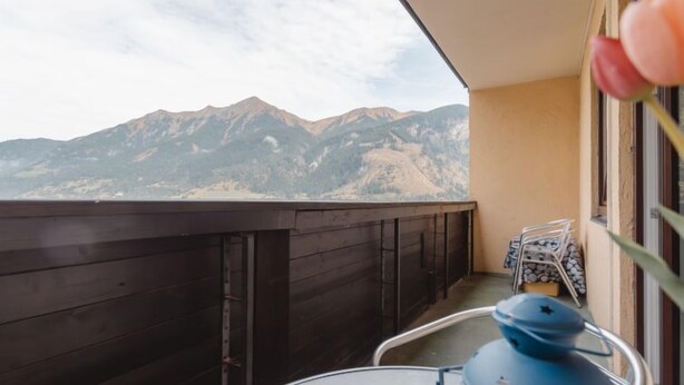 A balcony with a view of mountains, a small table, and a chair. - Apartment Smilla by Interhome (Bad Gastein)