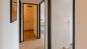 A hallway with a wooden floor, a white door, and a framed picture on the wall. - Apartment Smilla by Interhome (Bad Gastein)